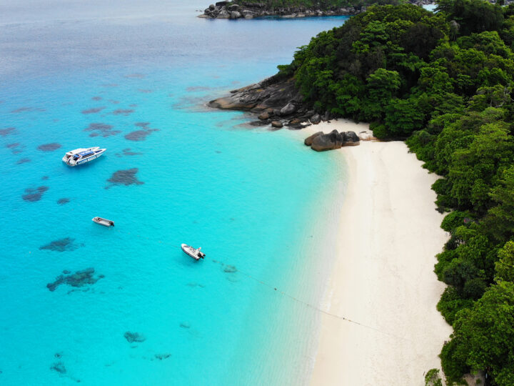 Similan Islands Thailand white sand beach teal water boats docked and lush tree line
