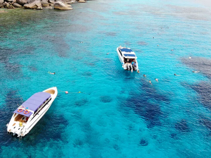 Similan Islands snorkeling view of two boats with people in blue water snorkeling