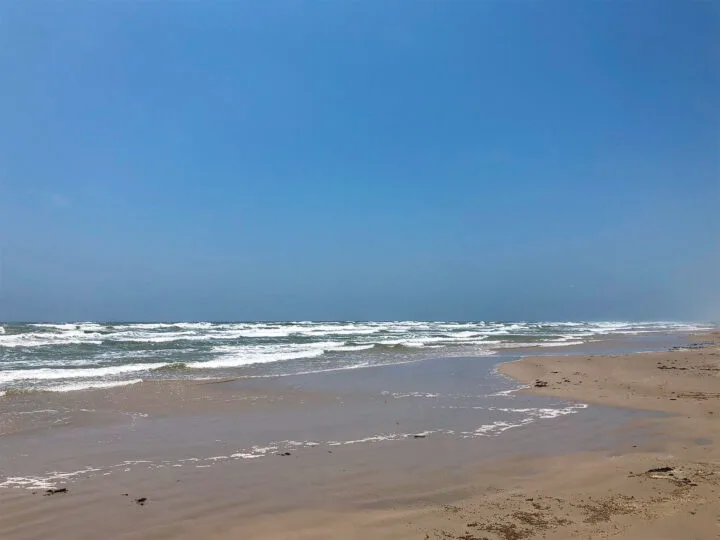 tan sand white waves blue sky