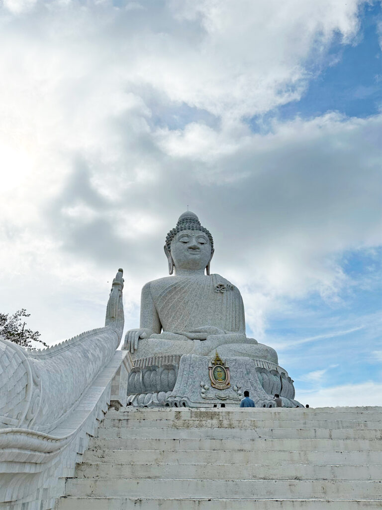 big buddha statue with stairs and sky in background
