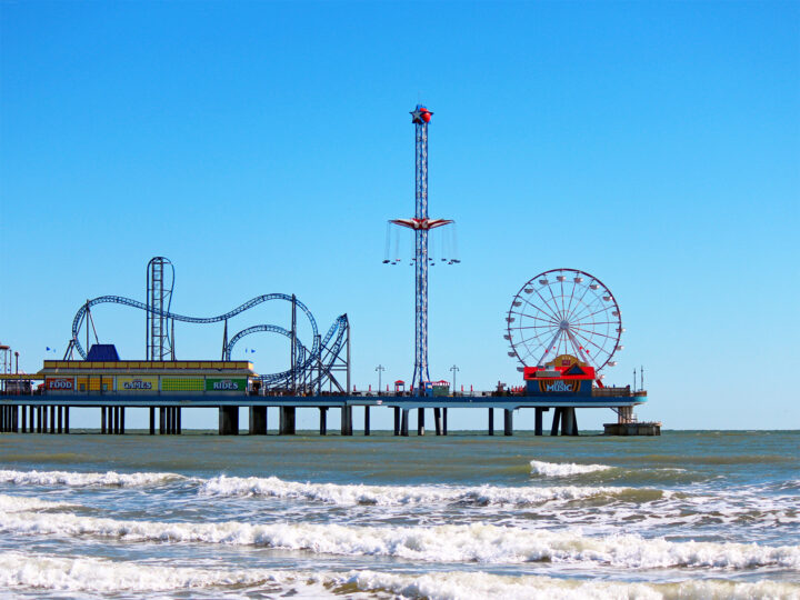 beaches on the gulf coast view of amusement park on pier with ocean waves in Galveston Texas