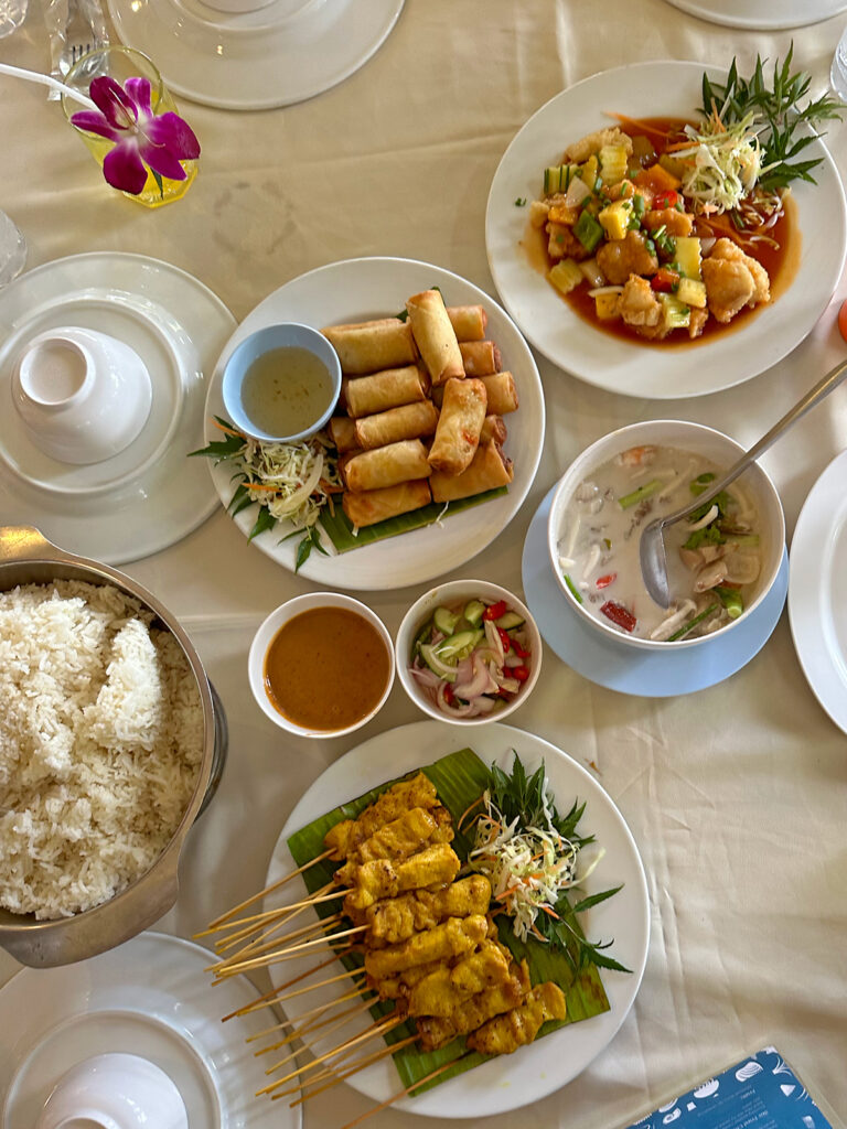 various Thai food on table with white dishes and tablecloth at restaurant in kahung beach
