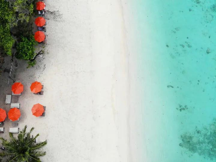 view of white beach teal water orange umbrellas