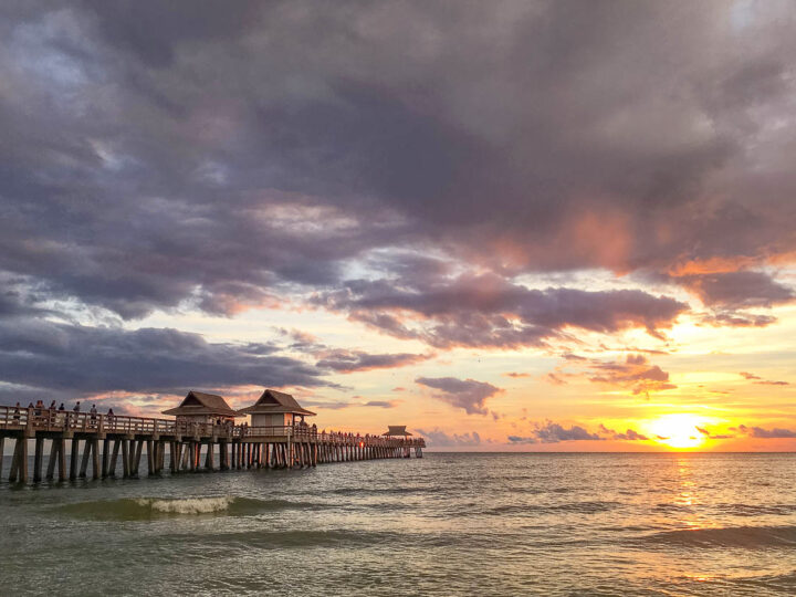 pier at sunset with moody sky and ocean view of one of the best beaches on the gulf coast