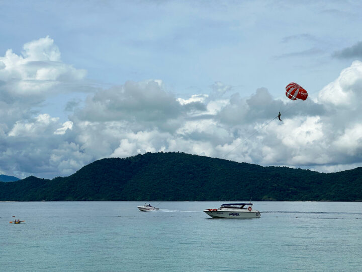 things to do in Coral Island Phuket parasailing with boats in water man hanging from balloon in air