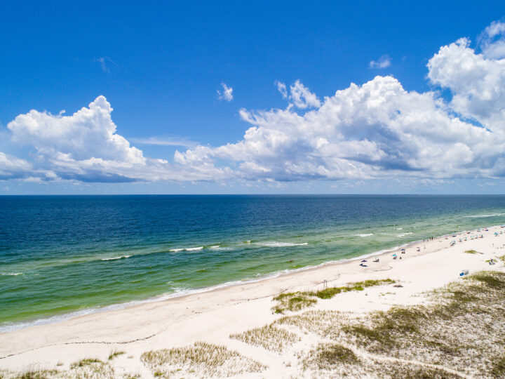 best gulf coast florida beaches view of sand dunes white sand emerald water puffy clouds in sky