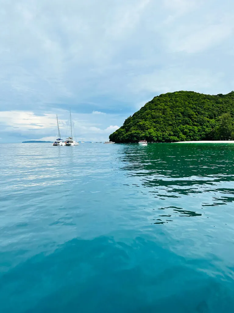 coral island from phuket view of blue water boats and land in distance on cloudy day