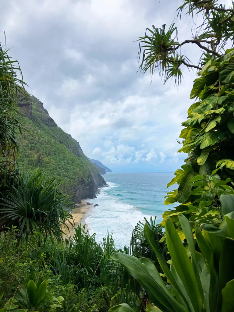 kauai vs maui view of coastline with lush foliage white waves on cloudy day