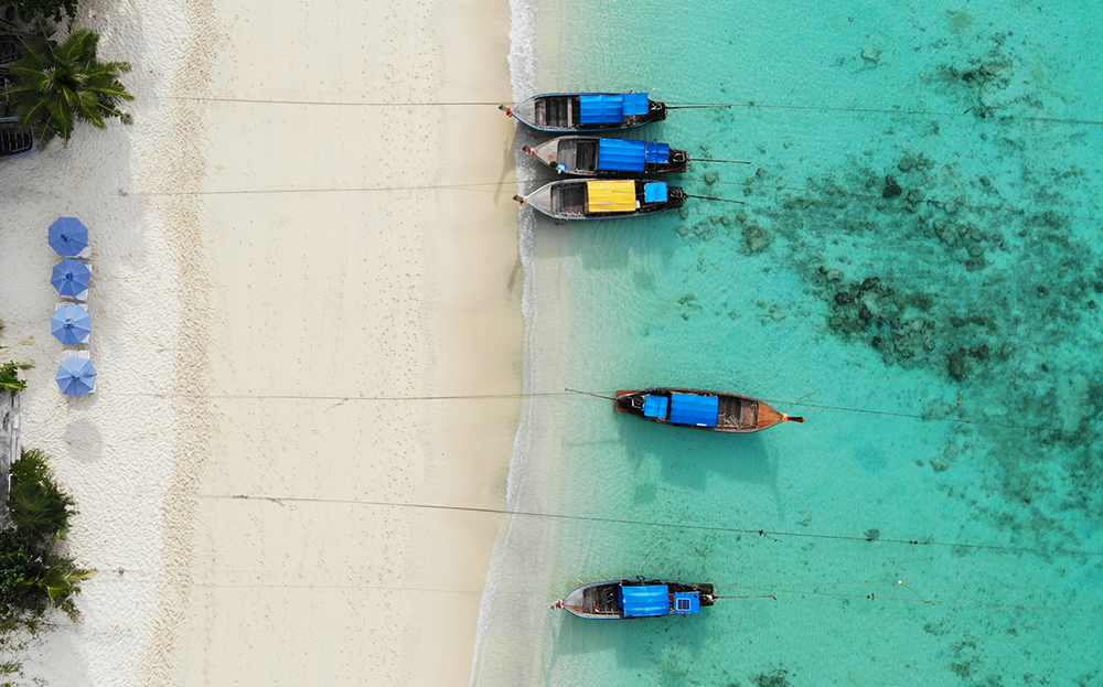 Krabi Thailand travel guide view of beach with blue umbrellas and long tail boats from above