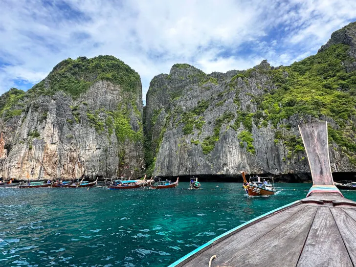 things to do in phi phi islands view of boat front with more boats on teal water bay and island in distance