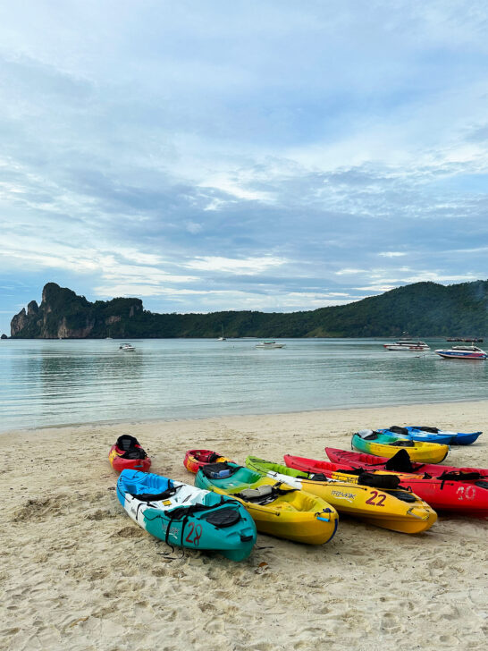 things to do in Phi Phi Islands view of kayaks on beach with water and hillside in distance