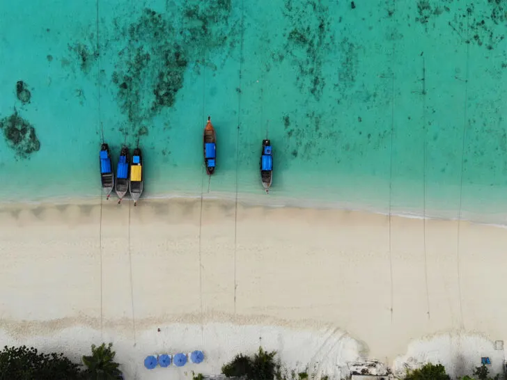 Thailand beaches longtail boats on beach with sand and teal water looking down