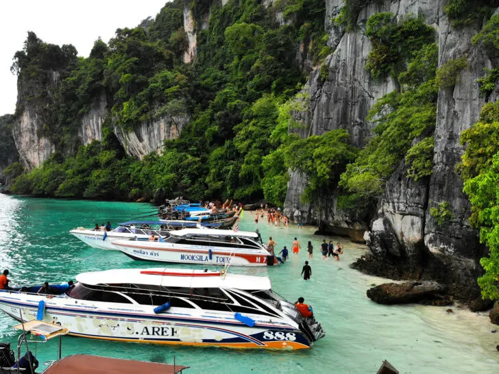 boats near shore with people looking for monkeys in water at Monkey Beach Thailand