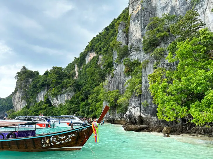 long tail boat along rocky shore in thailand 
