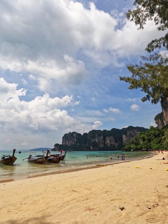 view of boats and people in water with yellow sand and coastline railway beach Krabi thailand