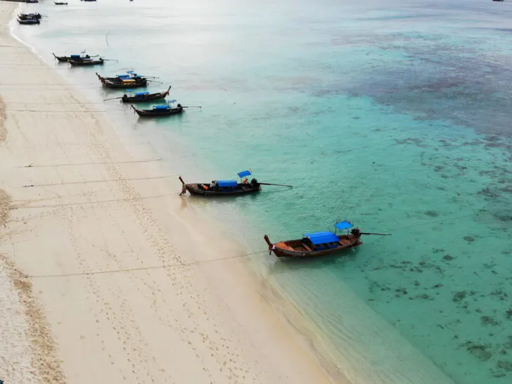 boats on the beach in thailand with teal water