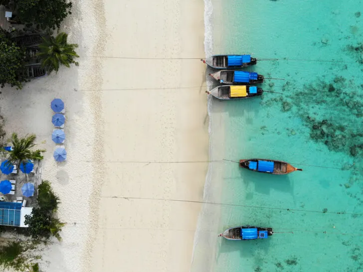 drone view of tan sand and boats with teal water in Thailand after researching international drone laws