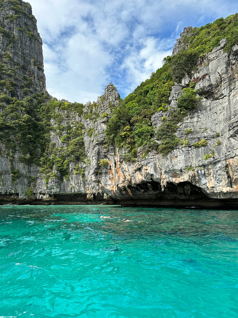 things to do in Phi Phi Islands view of snorkeling bay with teal water limestone cliffs