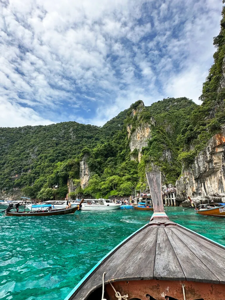 things to do in phi phi islands visiting Maya bay with boat arriving at entrance with other boats and line of people