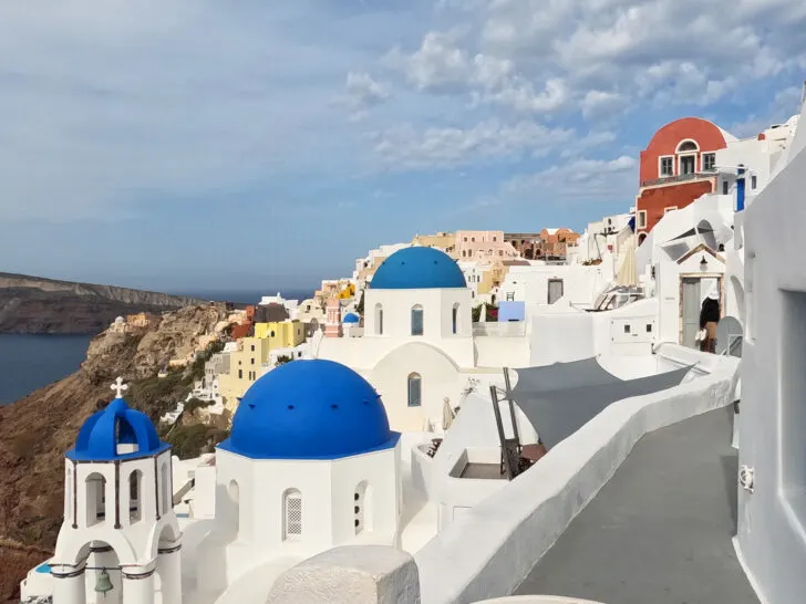 Mykonos vs Santorini view of Santorini skyline with grey and white city with blue and colorful accents