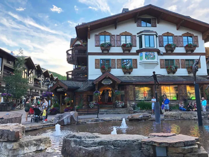 building with wood shutters and water fountain in foreground with people near, best colorado mountain towns