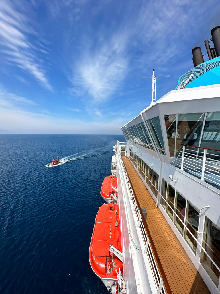 cruising Aegean Sea with ship deck orange boats and smaller boat in distance