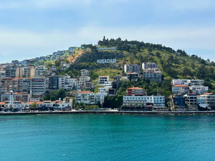 Celestyal Cruises Review Turkey port of Kusadasi with town sign and buildings with teal sea