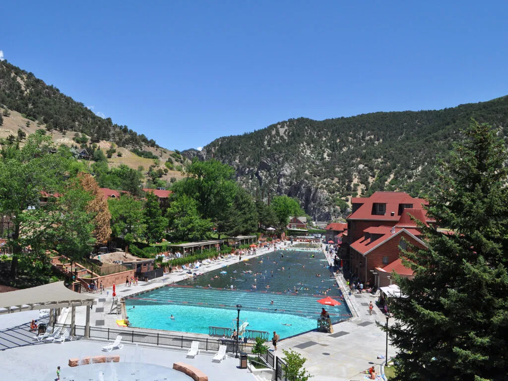 large hot spring pool in mountain scene with red buildings nearby best mountain towns colorado