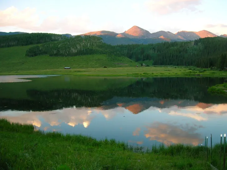 lake and mountains reflecting in water at sunset