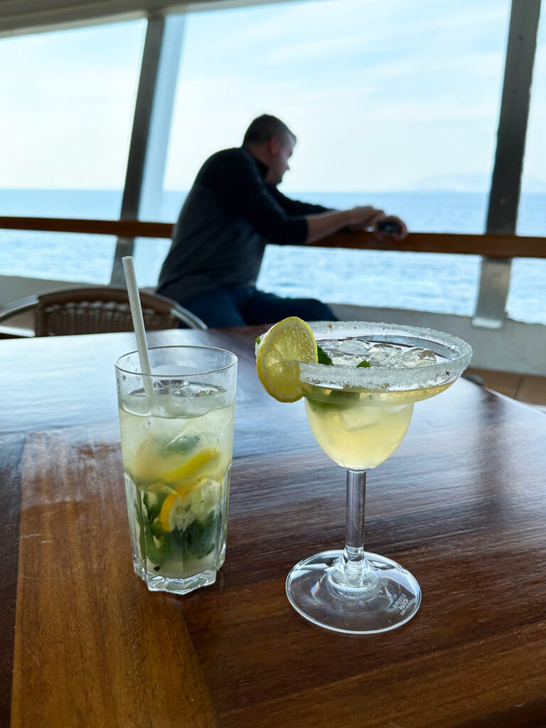 cruise Greek islands view of mojito and margarita on table with man in distance