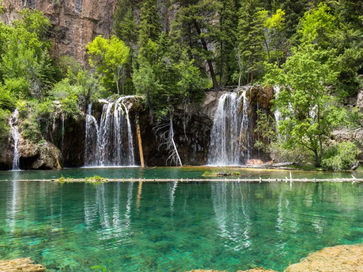 7 day colorado road trip itinerary with waterfalls down slope into teal lake