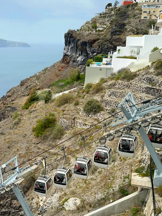 Santorini gondola to catch a ferry with gondola on wires on hillside and houses in distance