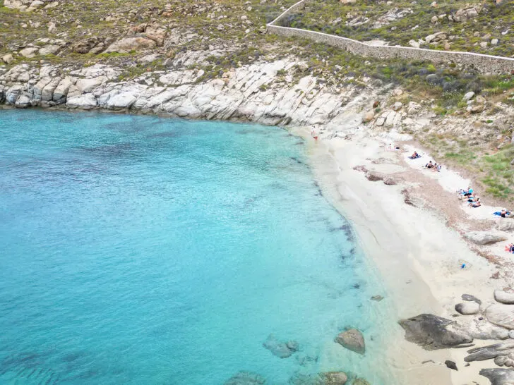 Mykonos and Santorini view of white sandy beach with rocks blue water and coastline