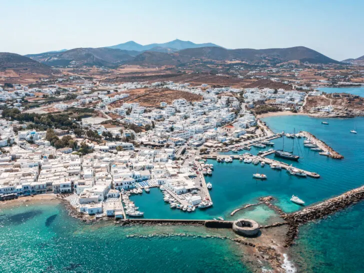 photo of best place in greece for couples with white buildings in village along shore and harbor blue water