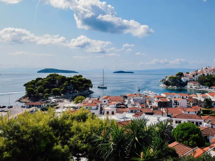 seaside village with orange rooftops and blue water white buildings with tropical plants best greek islands for couples