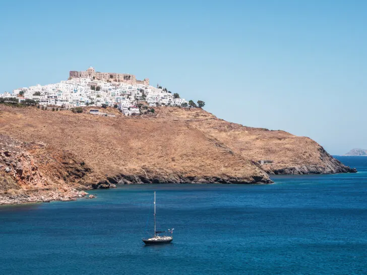 village in Green up on hill with blue ocean and boat best greek islands for couples