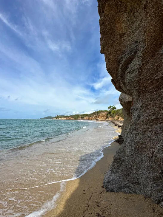 cliff and beach with waves blue sky