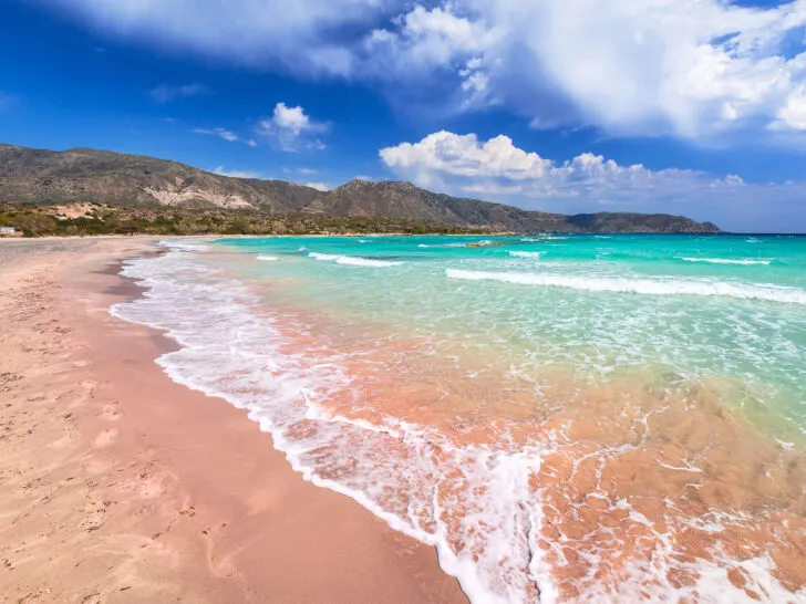 pink sand teal waves and island in distance best greece holidays for couples