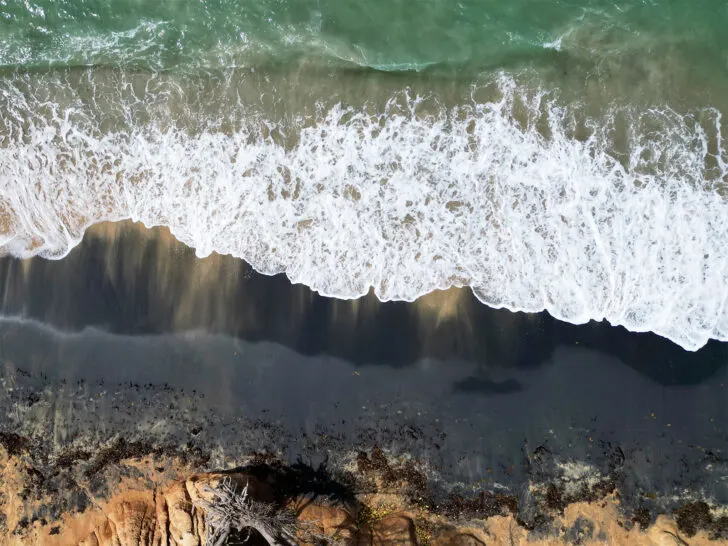 black sand beach vieques view from above of teal water white wave and black sand tan shore