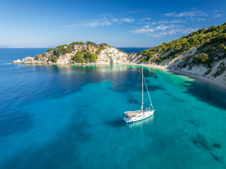 best Greek islands for couples with boat in bay along beach with azure water and beautiful coastline