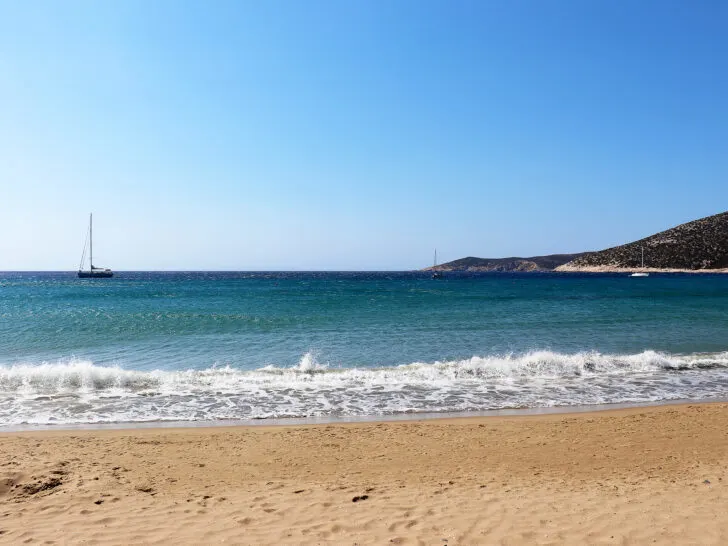 tan sand, blue ocean waves and blue sky at the best greek island for honeymooners