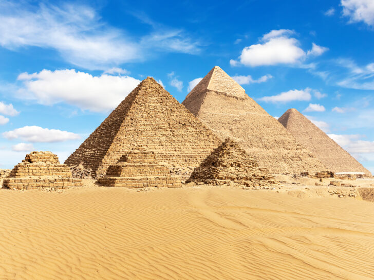Pyramids of Giza in Egypt with 3 large and 3 small pyramids with sand and blue sky