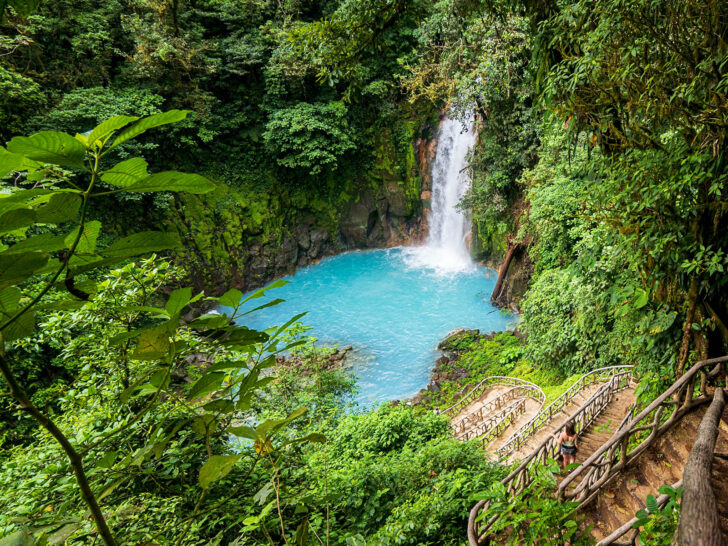 40th birthday trips rio celeste in Costa Rica view of water falling into blue pool of water in lush rainforest