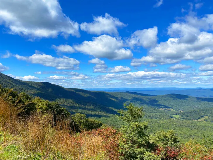 best October vacations usa view of mountains with green trees and red bushes on partly could day