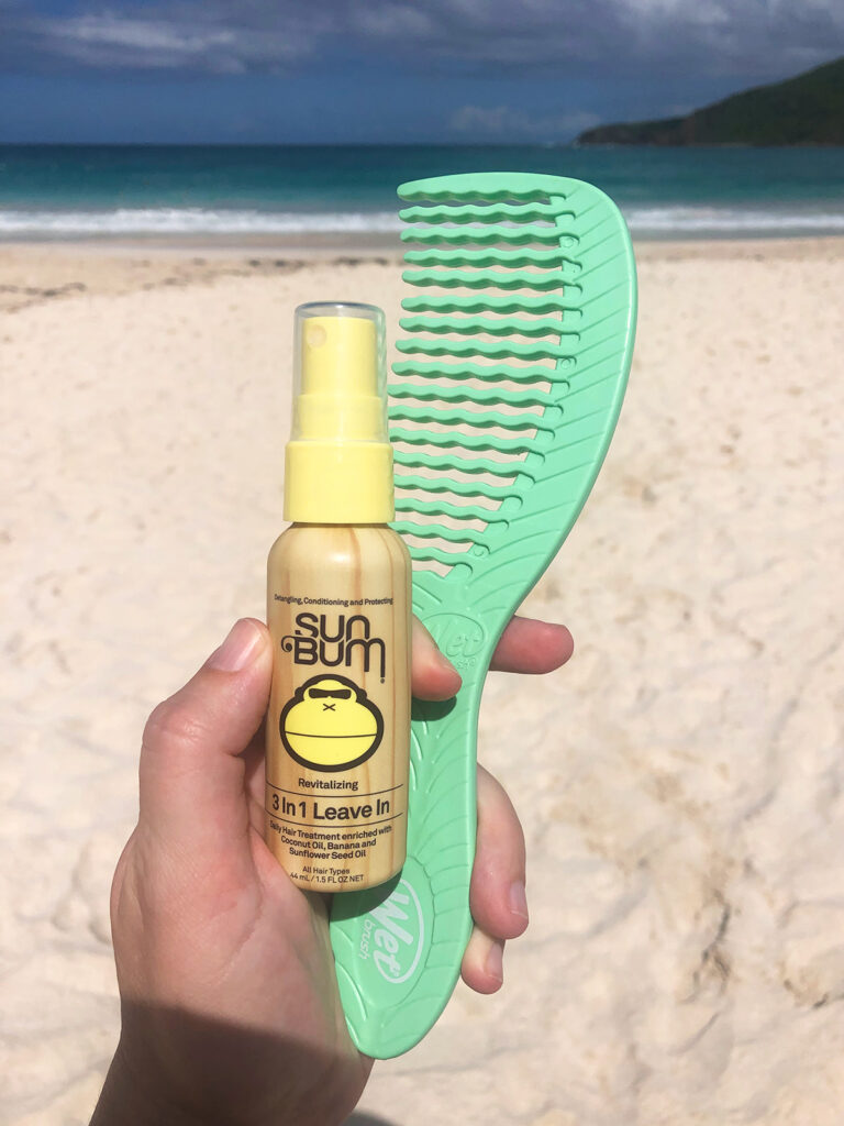 hand holding hair conditioner and comb at beach in Puerto rico