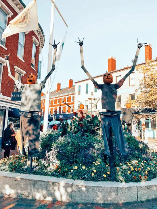 halloween scene with scarecrows pumpkin heads and city corner behind