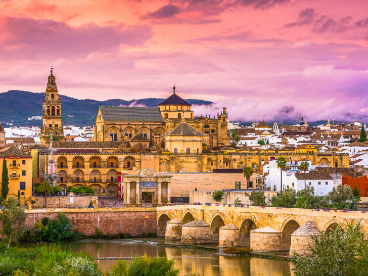 unforgettable 40th birthday ideas for her view of city in Spain with stone bridge old buildings and pink sunset
