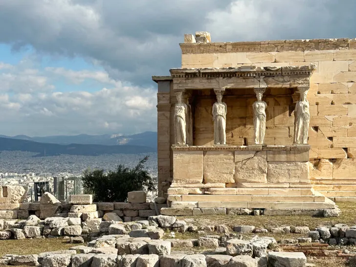 view of stone building with women statues and city in distance during 2 days in Athens