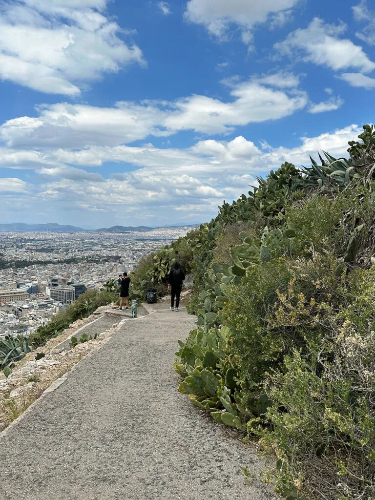 best time to visit athens greece on a sunny day walking down a hill with city in distance