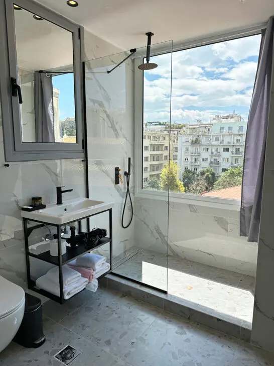hotel room with sink mirror towels shower with a view